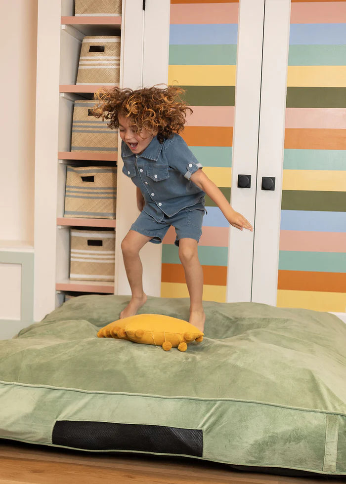 Child jumping on a bed with colorful striped wall in the background