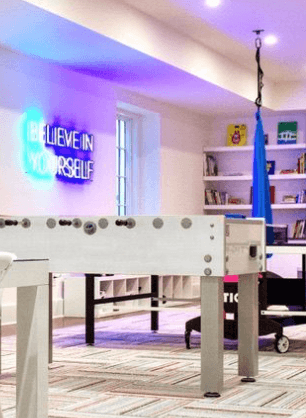 Brite Lite Tribe be kind neon sign illuminating a modern recreational room