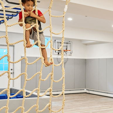 Child playing on a Jammar climbing cargo net for playroom, enhancing fun and physical activity