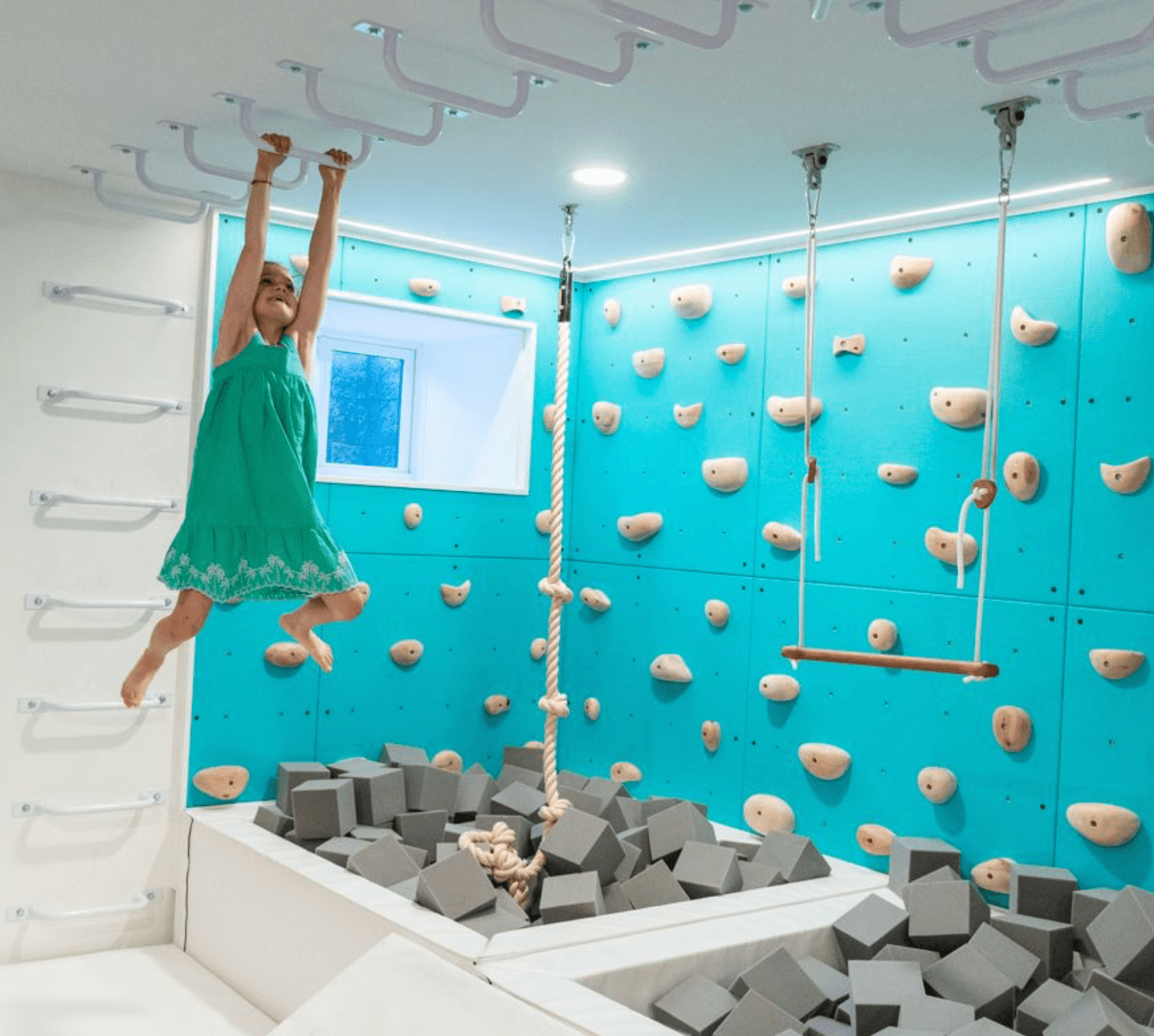 A child enjoying a climbing playroom design package with climbing walls and soft foam blocks