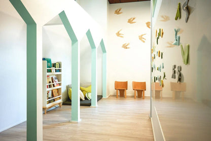 Bright communal playroom design featuring arched walls, soft seating, and creative decor for children