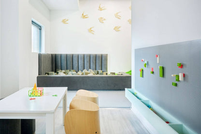 Bright and modern communal playroom design featuring gray seating and interactive play areas