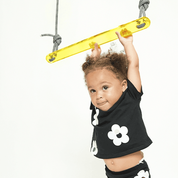 Child playing on a designer popsicle trapeze swing with colorful design for indoor fun