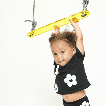 Child playing on a designer popsicle trapeze swing with colorful design for indoor fun
