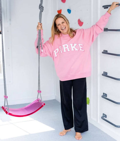 Happy woman in pink sweatshirt enjoying the designer scoop swing for playroom indoors