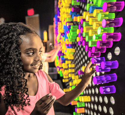 Child using the Lite-Brite peg set for kids on a large colorful display wall