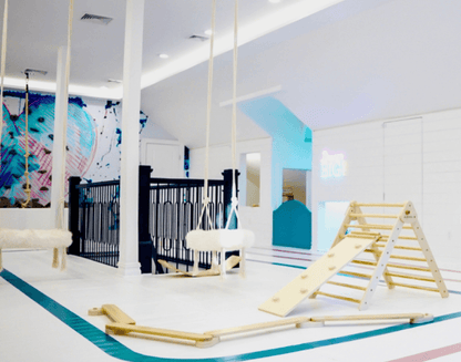 Colorful love heart wall mural in a playful indoor space with swings and climbing frame