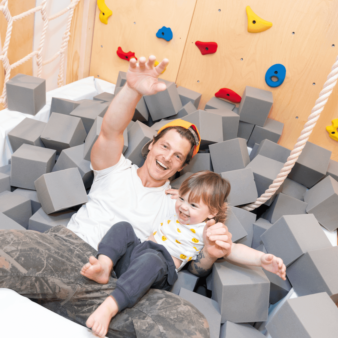 Child and adult playing together in a pit filled with Montessori foam cubes for safe, fun activity