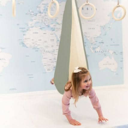 SAVOIZ sensory swing for kids in a playful indoor setting with a child exploring it